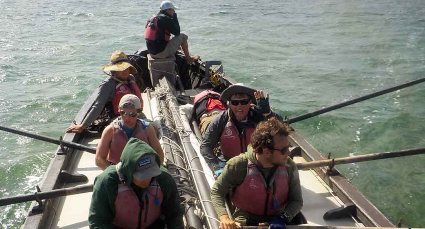 a small group of people navigate a sailboat on an outward bound expedition in florida